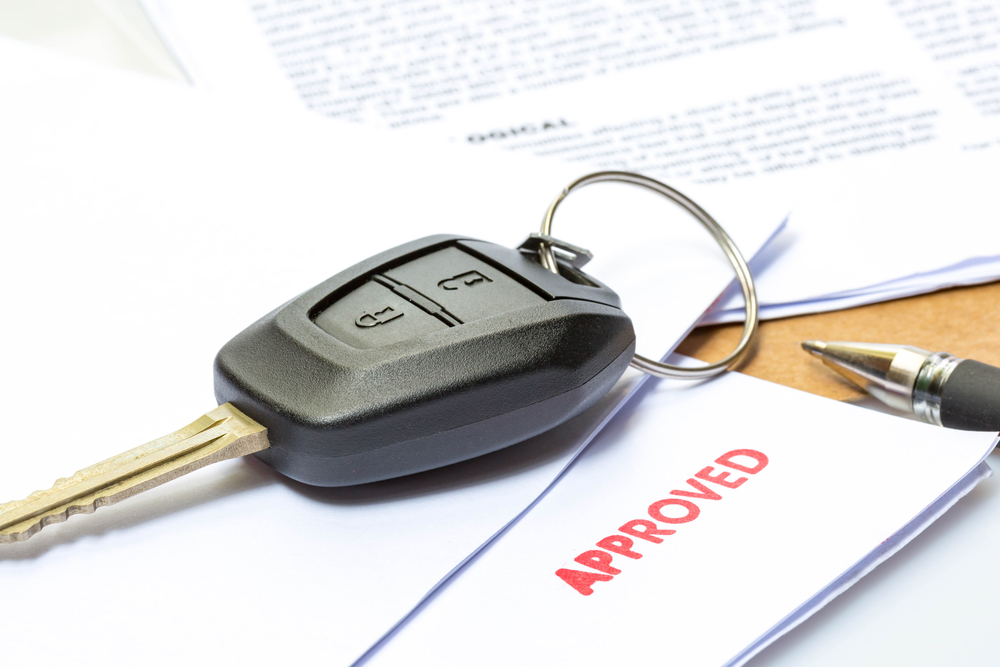 A finance sheet with car keys on top of it, labeled "APPROVED"