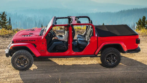 A photo of a red 2023 Jeep Gladiator driving down a dirt road near Redford, MI