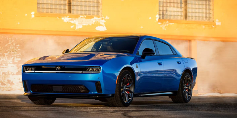 The image features a striking blue Dodge Charger, highlighting its powerful and dynamic design, set against an industrial background that complements its bold and aggressive stance.
